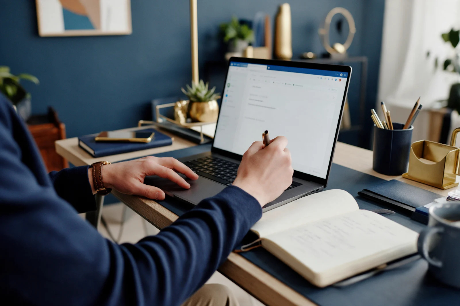 Consultant writing a personal email pitch to a journalist on a laptop, with a notebook of story angles beside the keyboard