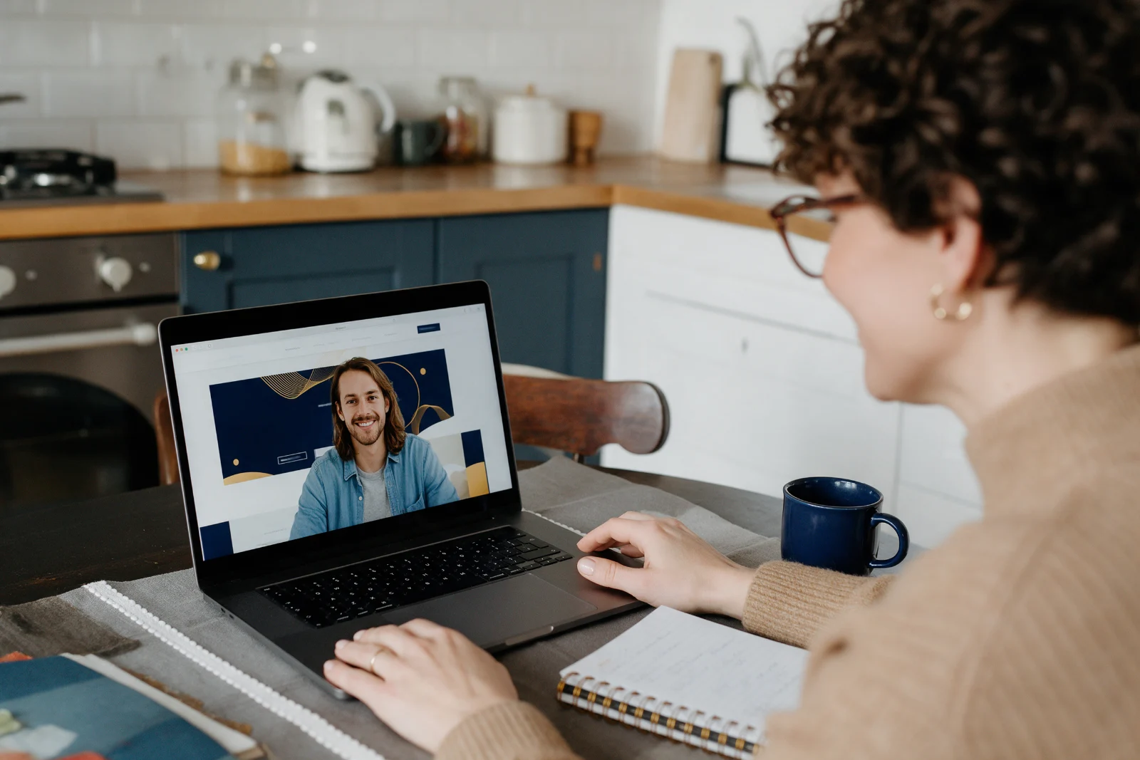 Small business owner on a video call with a web designer, an unfinished website draft open on the laptop screen